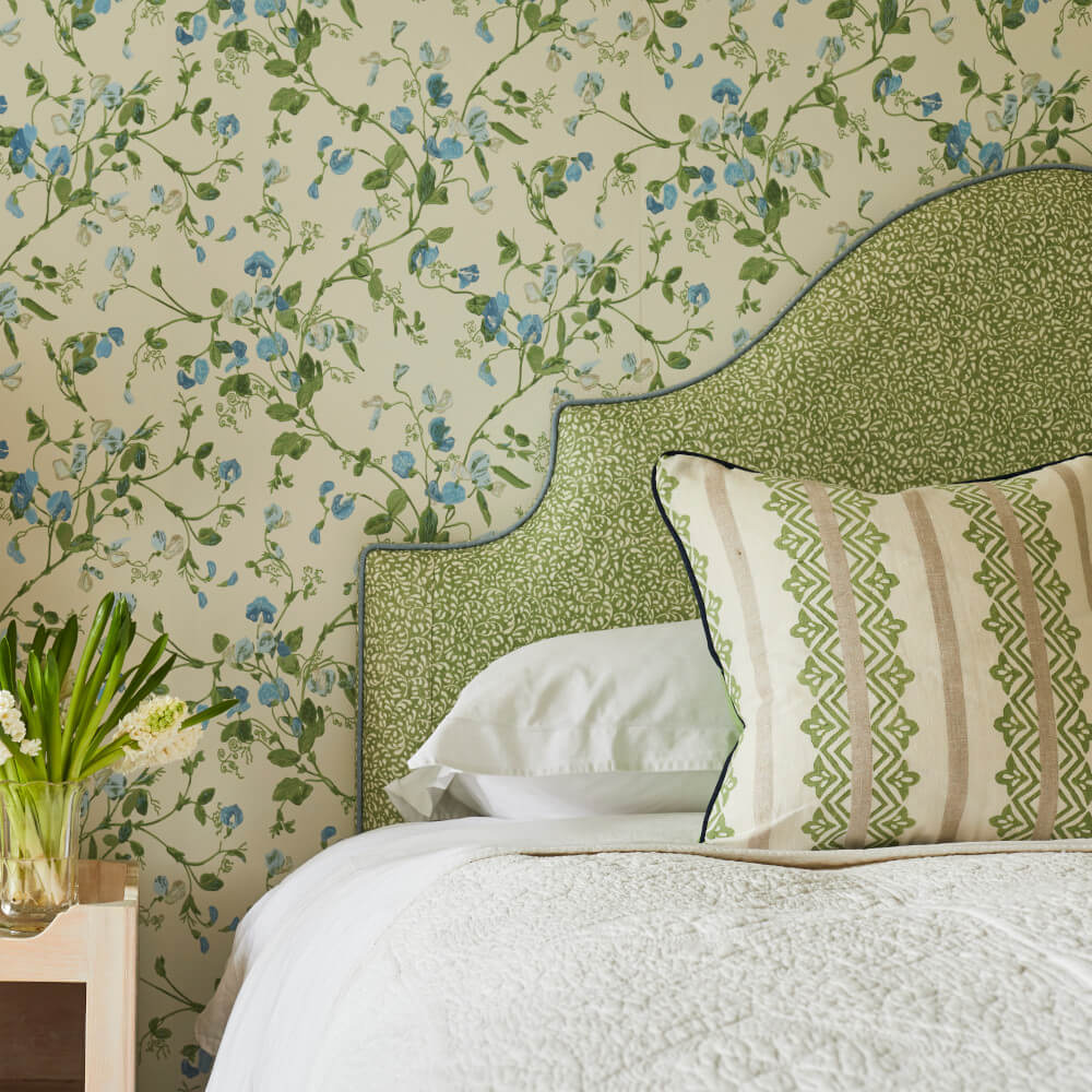 Bedroom with floral wallpaper, a patterned headboard, and a decorative pillow on a neatly made bed.